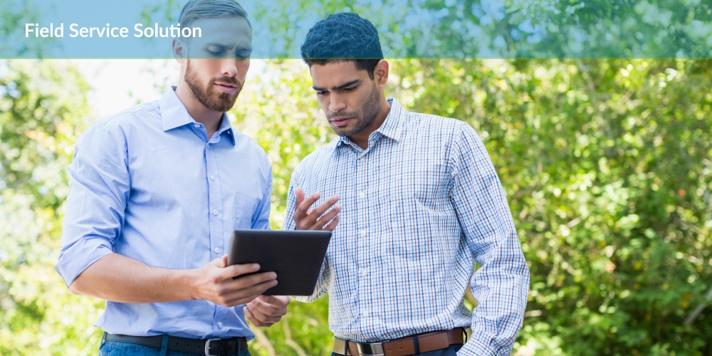 Two professionals engaged in a discussion over a field service solution on a tablet.
