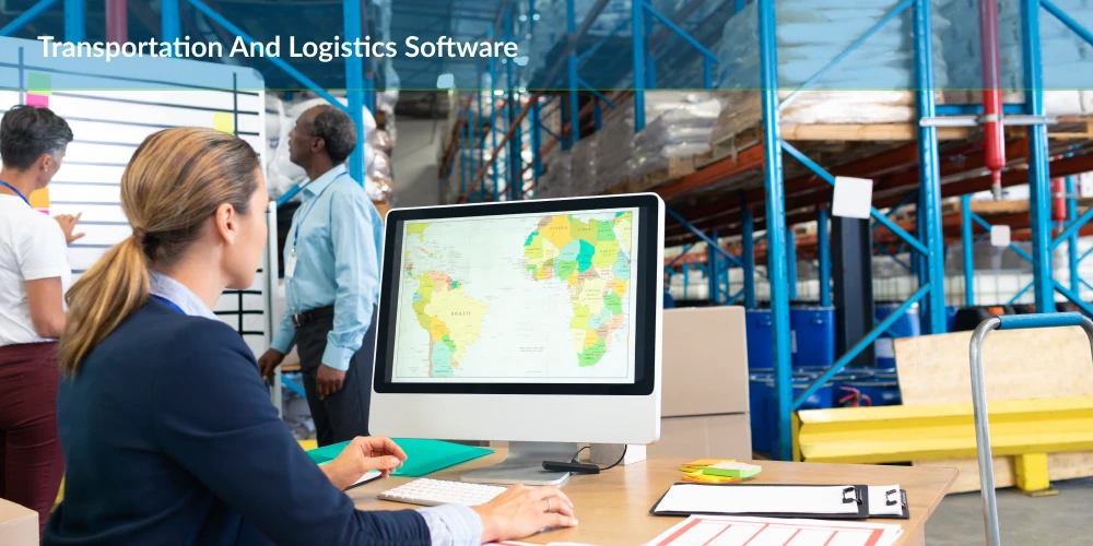 A logistics professional using transportation and logistics software on a computer in a warehouse environment.