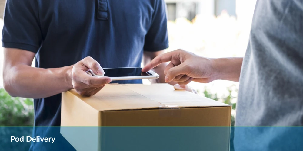 Delivery person handing over a digital device for signature with a package on the foreground.