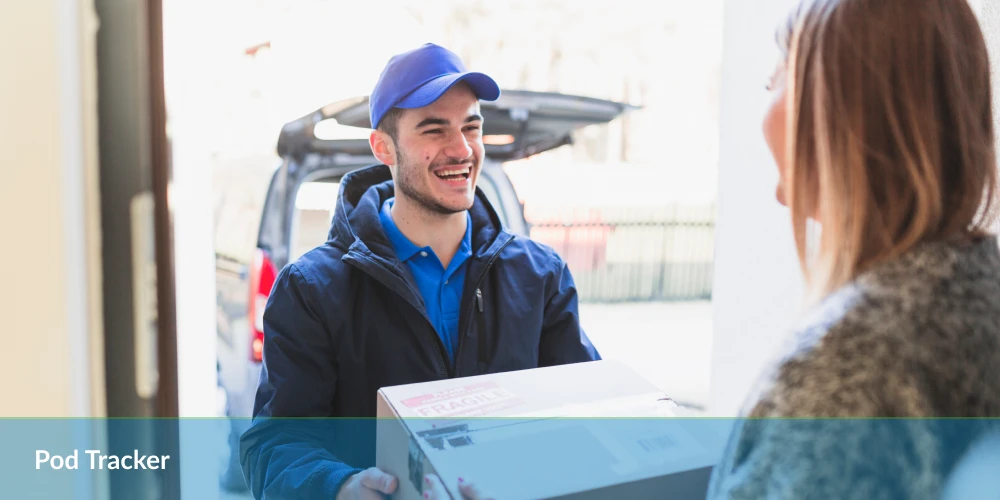 Delivery person in blue handing a package to a woman at the door.