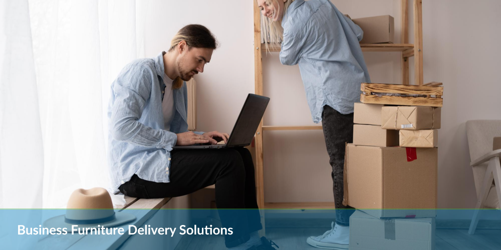 Two people with boxes in an office, one using a laptop, text 