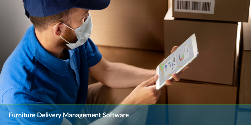 Furniture delivery management software : Delivery person in blue uniform using a tablet with map software beside cardboard boxes.