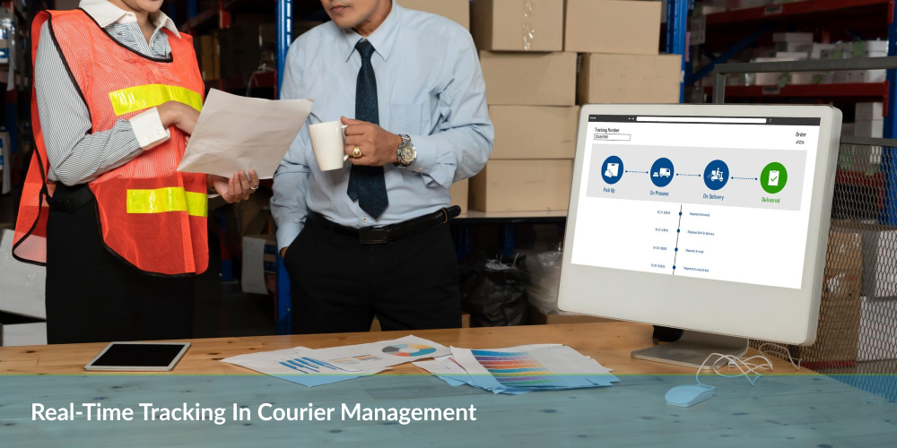 Two people discussing paperwork in a warehouse with a courier tracking system on a computer screen.