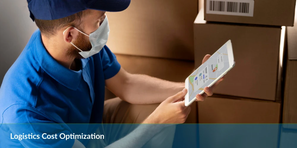 A man wearing a mask and blue uniform uses a tablet near stacked cardboard boxes, focusing on logistics cost optimization.